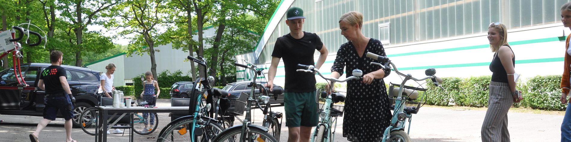 Eine Frau und ein Mann begutachten Fahrräder bei der mobilen Fahrradwerkstatt vor dem Gebäude des Sportvereins THK Rissen