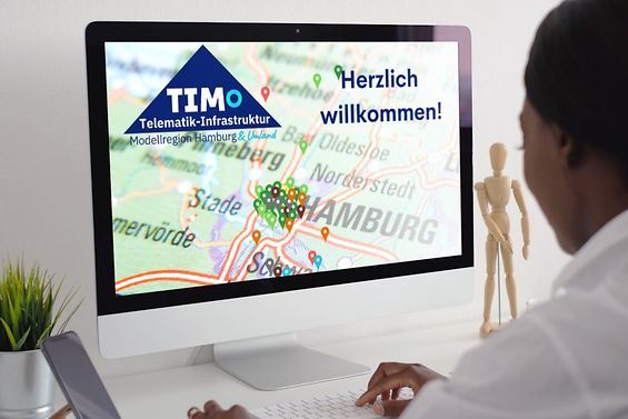 Frau am Desktop, auf dem Display ist das TIMO-Logo mit einer Karte des Modellreion